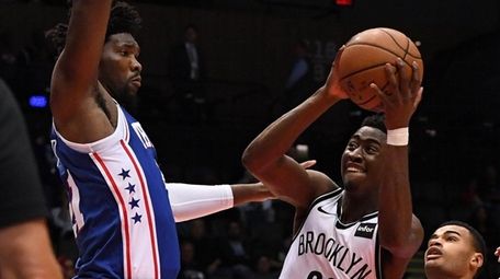 Nets guard Caris LeVert is defended by 76ers center
