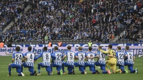 Hertha Berlin's players kneel down before the German