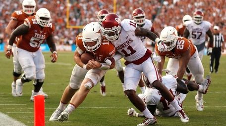 Texas quarterback Sam Ehlinger, center left, collides with