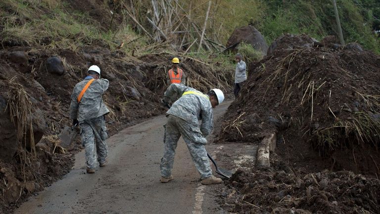 Soldiers shovel debris on a road near Adjuntas,