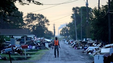 A man walks past debris from homes on