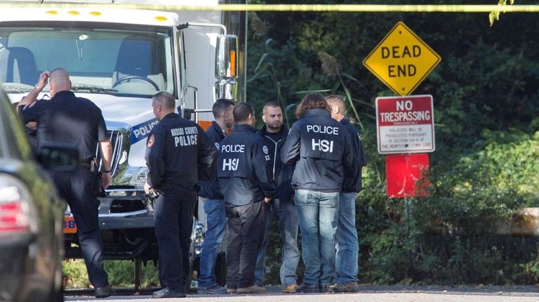 Investigators search a wooded area near the border