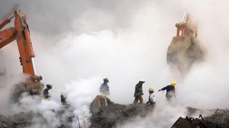 Firefighters make their way over the ruins of