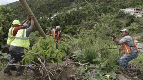 Workers in Puerto Rico work to return electricity.