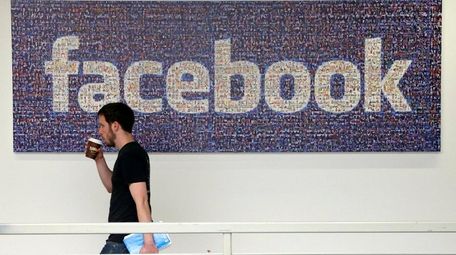 A Facebook employee walks past a sign at