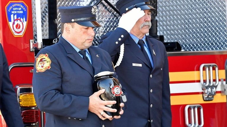 An FDNY firefighter carries the urn containing the