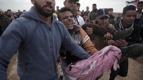 Palestinian protesters carry a wounded man who was