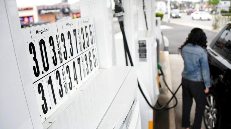 A woman pumps gas at a Shell service