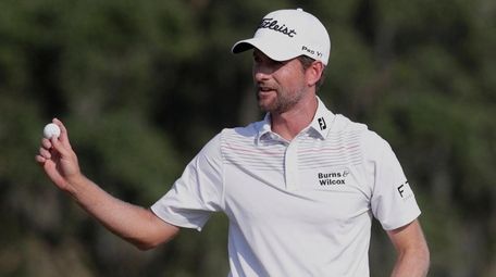 Webb Simpson holds up his ball on the