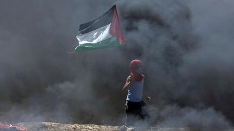 A boy waves a Palestinian flag while walking