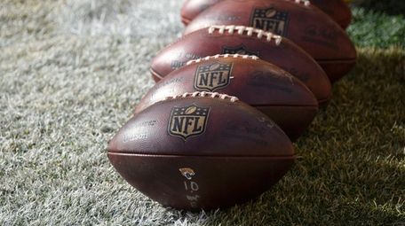NFL footballs sit on the field during warm-ups