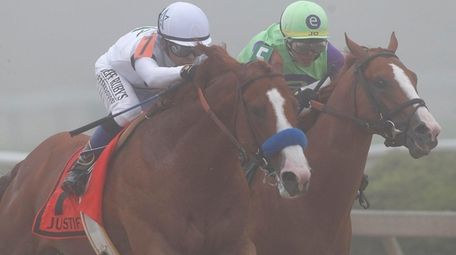 Justify, left, ridden by jockey Mike Smith, leads
