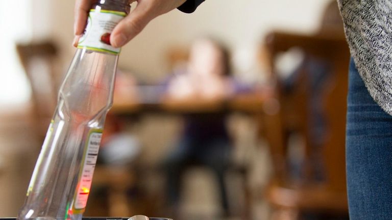 A woman tossing a bottle into a recycling