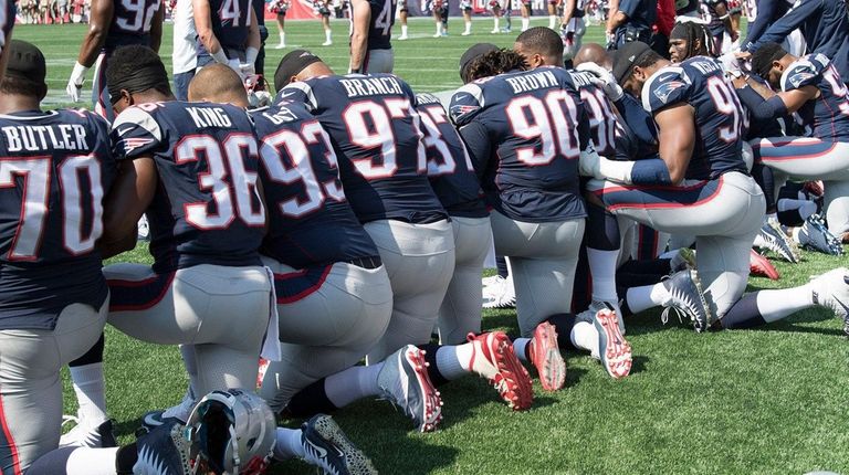 New England Patriots hold hands and kneel during
