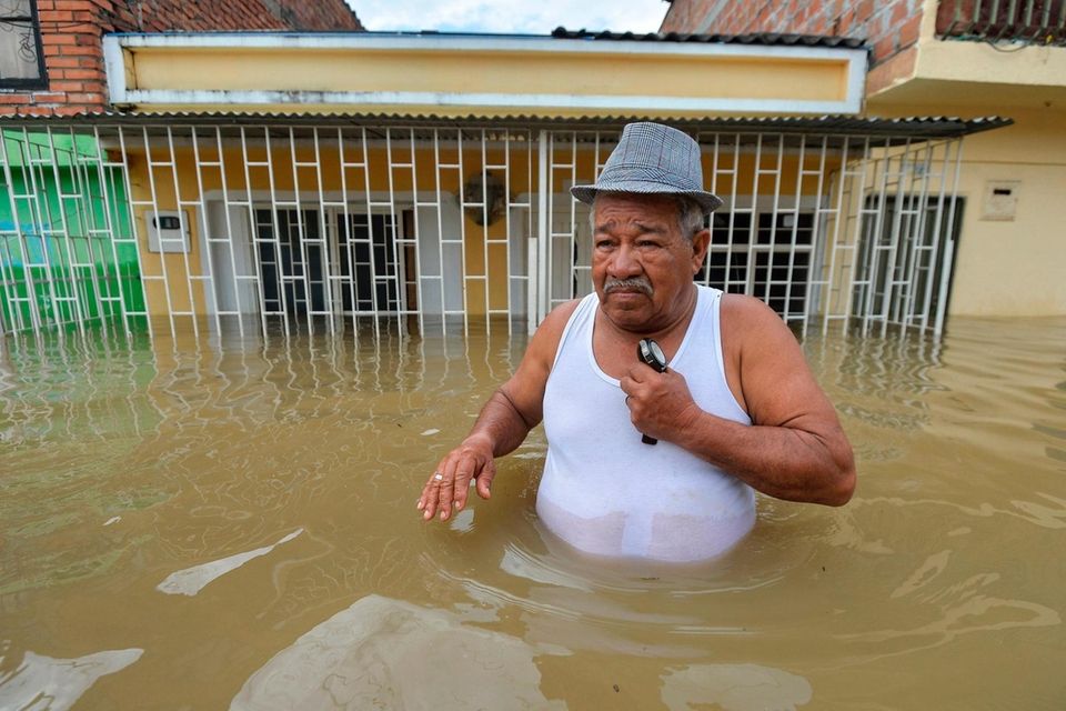 A man wades along a flooded street in