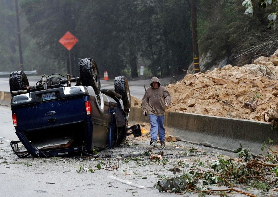 A tow truck operator walks past an overturned