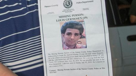 Luis Germosen holds a police poster of his