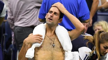 Novak Djokovic sits with an ice towel around
