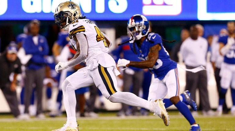 Alvin Kamara, left, scoots past Giants DB Curtis