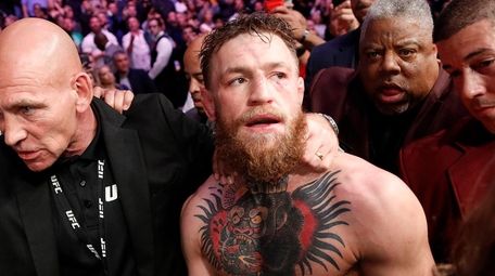 Conor McGregor is escorted from the cage area