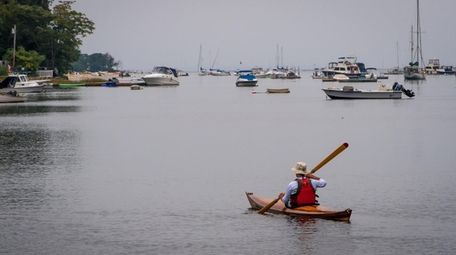 A kayaker glides along the still water of