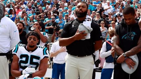 The Panthers' Eric Reid kneels during the national