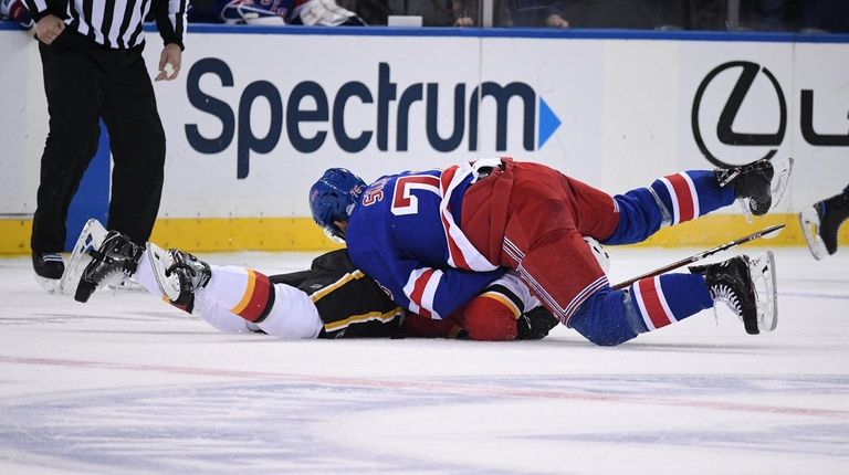 Rangers defenseman Brady Skjei tackles Flames defenseman Rasmus