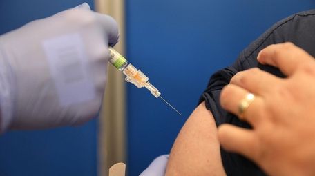 Mario Ancalmo receives an influenza vaccination from Raphael