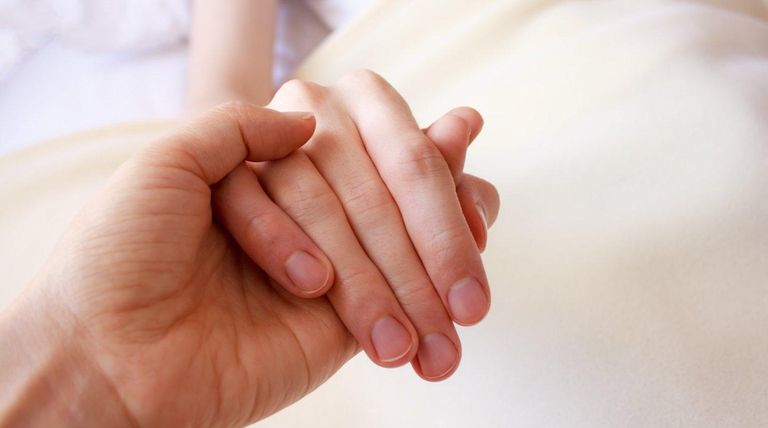 Man holding the hand of a sick loved