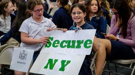 Students display signs as Gov. Andrew M. Cuomo