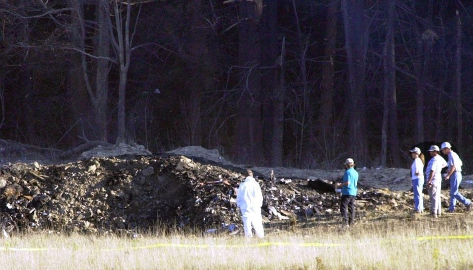 Emergency workers look at the crater created when