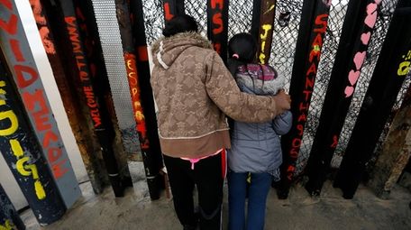 A Honduran migrant and her daughter peer through