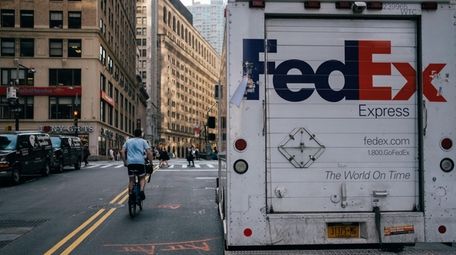 A person rides a bicycle past a FedEx