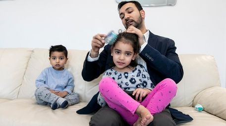Rehman Malik, 30, brushes his daughter Amirah's hair