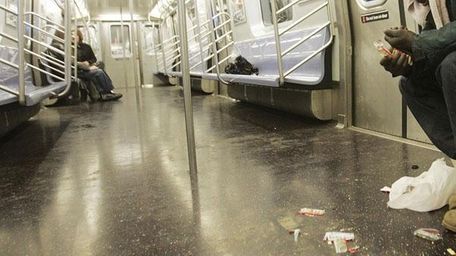 A subway car is littered by trash