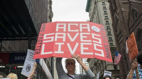 Participants hold signs while protesting the repeal and