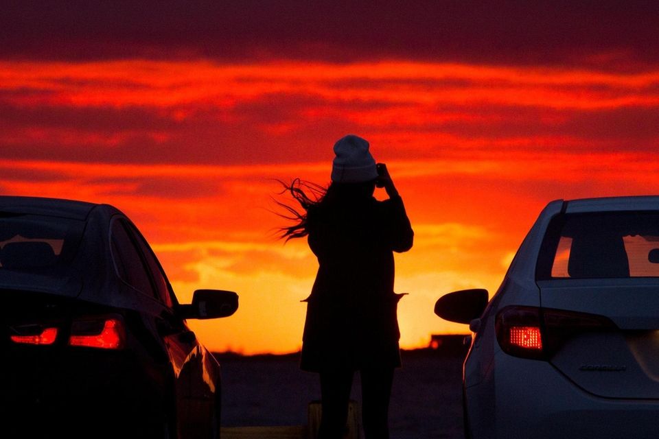 A woman photographs the sunset at Sampawams Point