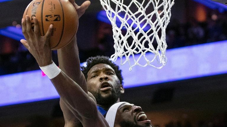 The 76ers' Joel Embiid, top, blocks the shot