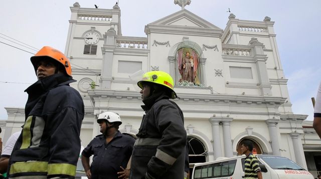 Sri Lankan firefighters stand in the area around... Sri Lankan firefighters stand in the area around