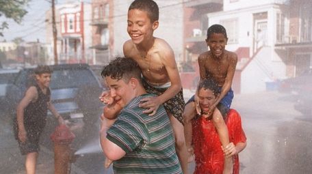 Kids in Corona, Queens, run through spray from