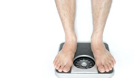 Legs of men standing on scales weight on