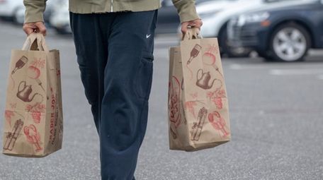 A shopper walks with paper bags outside Trader
