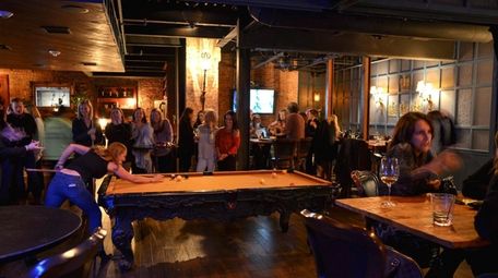 Patrons chat, sip drinks and play billiards inside