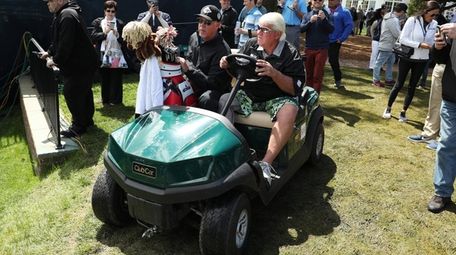 John Daly drives a golf cart during a
