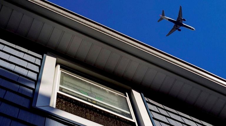 A large passenger jet passes over a home