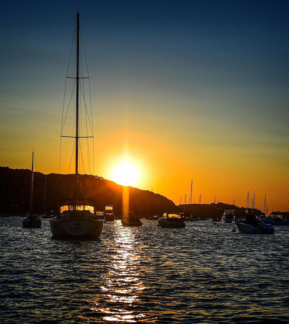 The sun sets behind boats moored in Northport