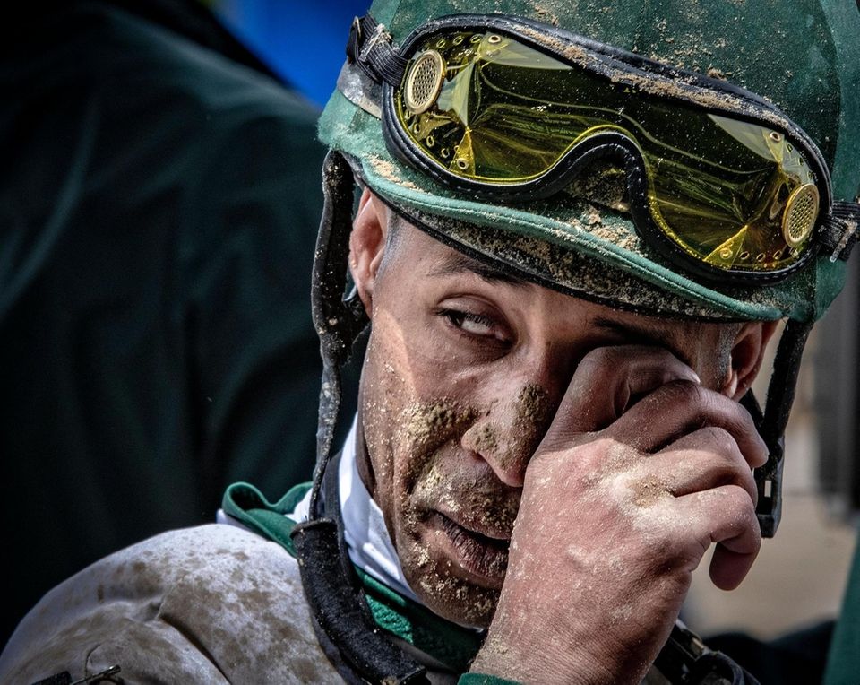 A jockey is covered in mud after his