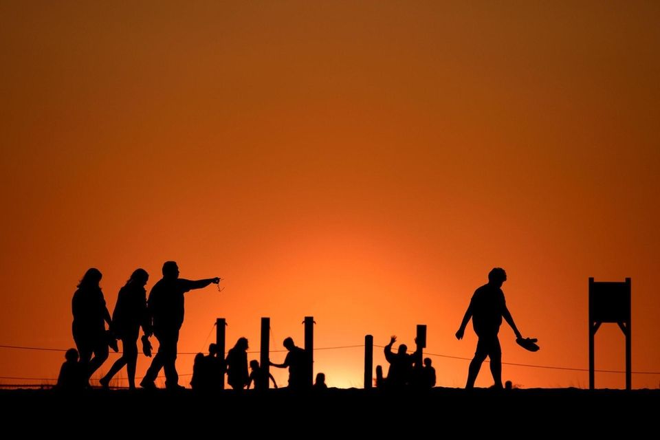 Beachgoers retreat as the sun sets at Robert