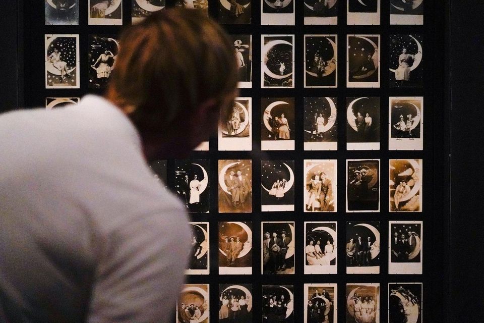 A person looks at Paper Moon Studio portraits