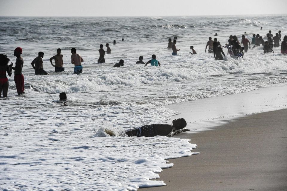 Beachgoers enjoys the waves in the evening at